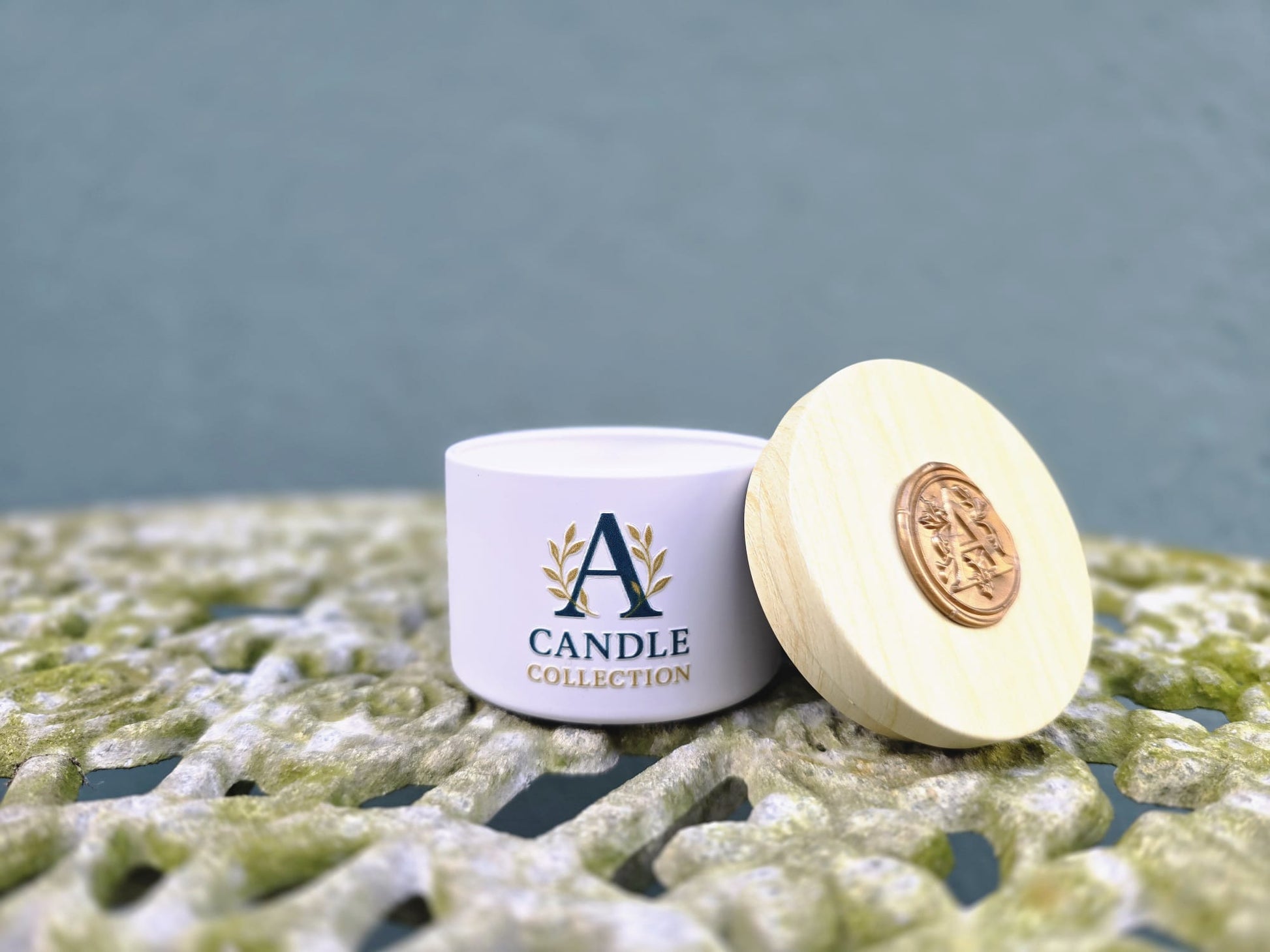 Świeca sojowa 90 g A Candle Collection w białym metalowym pojemniku z drewnianą pokrywką obok świecy